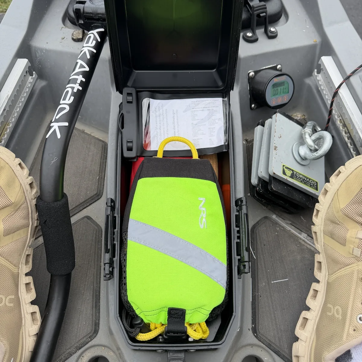 Waterproof first-aid kit stored in the hatch box directly in front of a fishing kayak seat