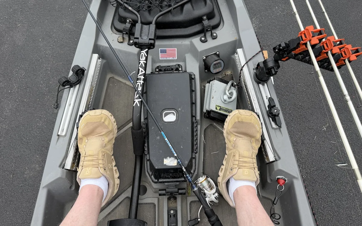 Fishing kayak cockpit showing anchor line, rods, wiring, and rigging around the seat